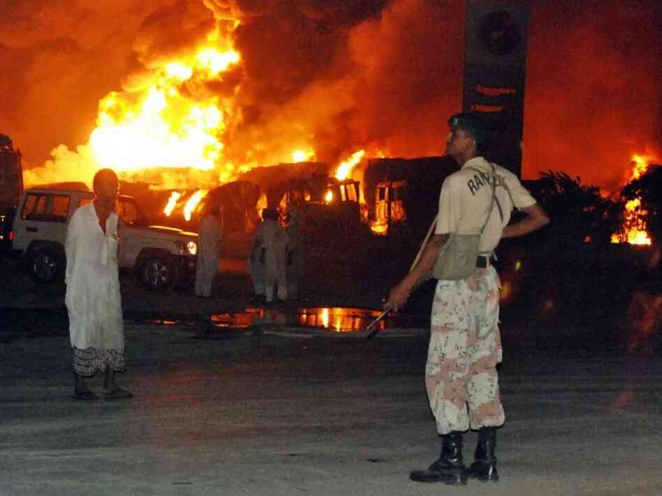 Pakistani paramilitary soldiers guard burning tanker trucks. Pakistani paramilitary soldiers guard burning tanker trucks.