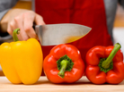 A woman holds a knife over a red pepper. A woman holds a knife over a red pepper.