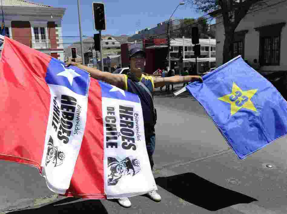 A peddler sells Chilean and Copiapo flags that say, "Welcome, Heroes of Chile" and "33" in Copiapo. A peddler sells Chilean and Copiapo flags that say, "Welcome, Heroes of Chile" and "33" in Copiapo.
