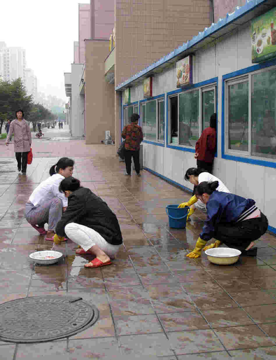 Women scrub the sidewalks of Pyongyang by hand.
