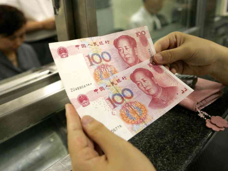 A woman examines two 100 renmenbi notes. A woman examines two 100 renmenbi notes.