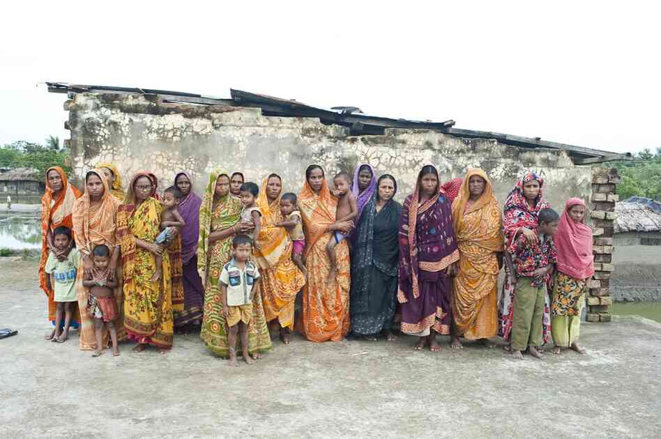 Eighteen widows of tiger victims pose for a portrait; the youngest is 22 years old. One woman lost her husband two months ago. They are part of a struggling self-help group run by an NGO.