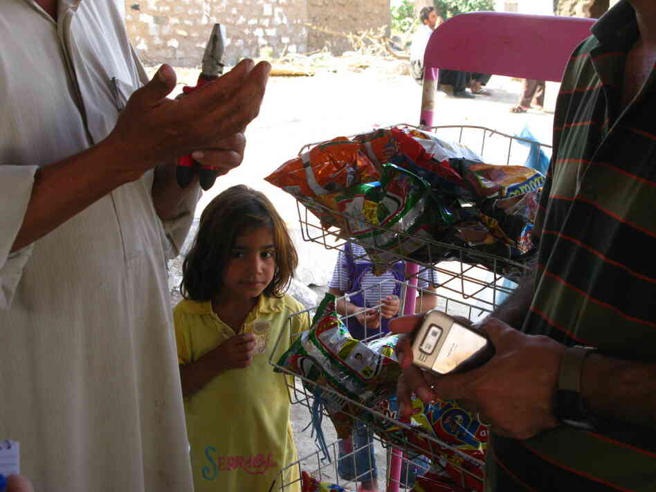 A young girl waits to buy snacks from an Arab man. A young girl waits to buy snacks from an Arab man.