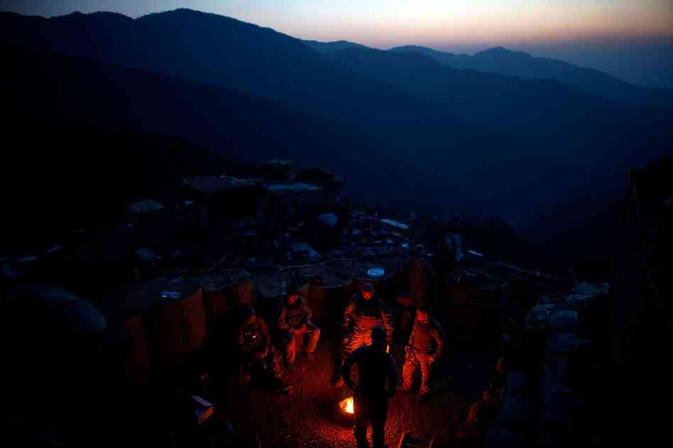 Members of Alpha Company at an abandoned military outpost, where they are holding a secure position for the team rescuing the downed helicopter. The soldiers make a small fire to keep warm at the outpost, nearly 8,000 feet in altitude, while waiting for Afghan border guards to come secure the area.
