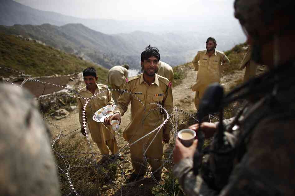 A member of Pakistan's paramilitary Frontier Corps passes tea to Lt. Kenneth Kovach through coils of wire separating Afghanistan and Pakistan. Elements of the Taliban and al-Qaida are believed to cross the border here from safe havens inside Pakistan.