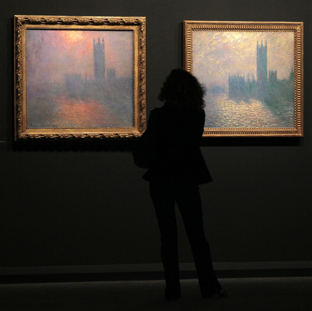 A woman looks at two paintings by Monet.