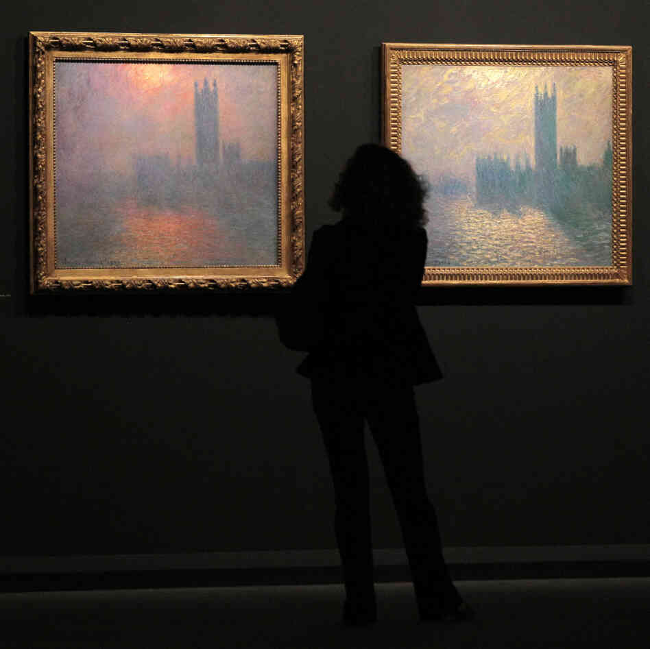A woman looks at two paintings by Monet.