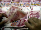 A Chinese bank staff counts stacks of 100-yuan notes A Chinese bank staff counts stacks of 100-yuan notes