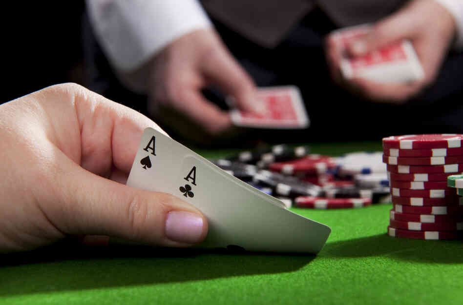 A woman holds a pair of aces at a poker table. A woman holds a pair of aces at a poker table.