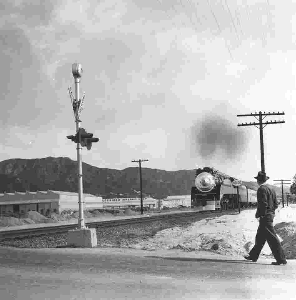 A man walks on an unidentified Burbank street. The Lockheed Aircraft plant and the Verdugo Mountains are seen in the background.