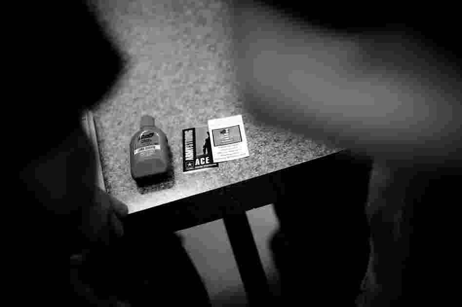 A bottle of hand sanitizer, a suicide prevention help card and an Army resource card on a table at the reception facility.