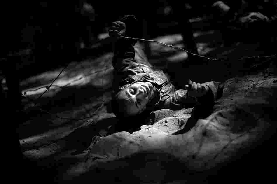 E2 David Mangold crawls on his back bellow barbed wire on a series of obstacles in a training lane.