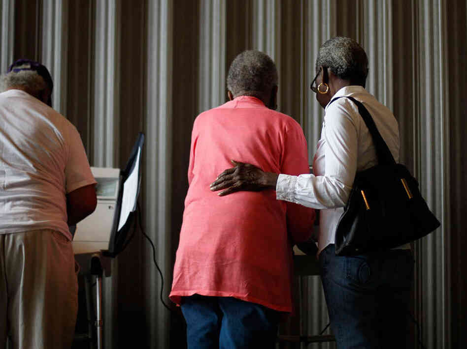 Marian Baker, 83, left, is assisted by Joann Lacy, 69, both of Atlanta, as she casts her ballot. Marian Baker, 83, left, is assisted by Joann Lacy, 69, both of Atlanta, as she casts her ballot.