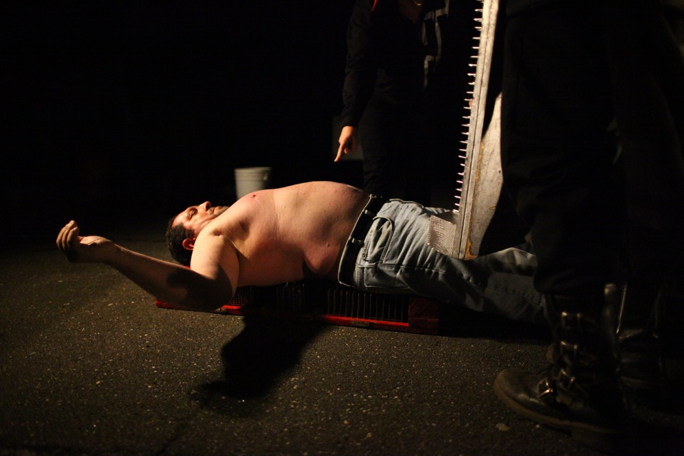 An entertainer prepares to have a board with nails pushed into his chest at the Pennhurst Asylum haunted tour.