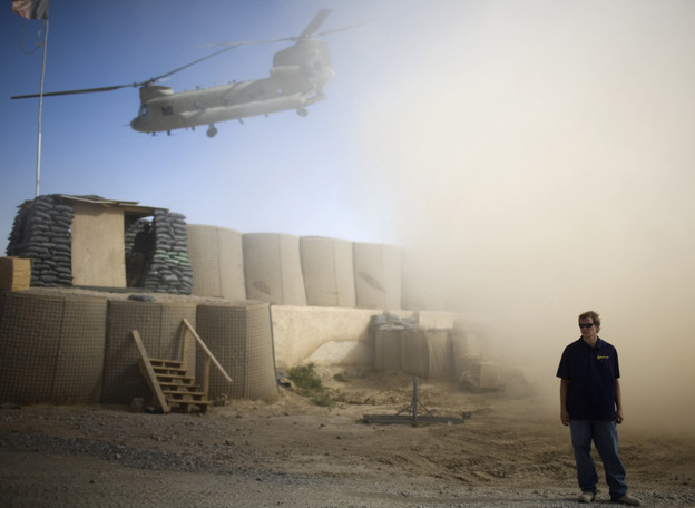 A U.S. contractor looks away from a dust cloud whipped up by a helicopter.