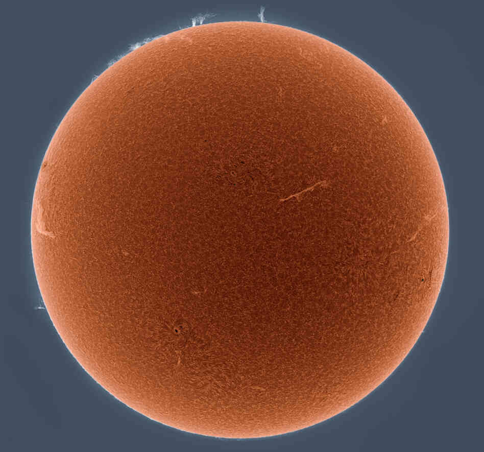 A portrait of the sun rendered in the hydrogen alpha spectrum.