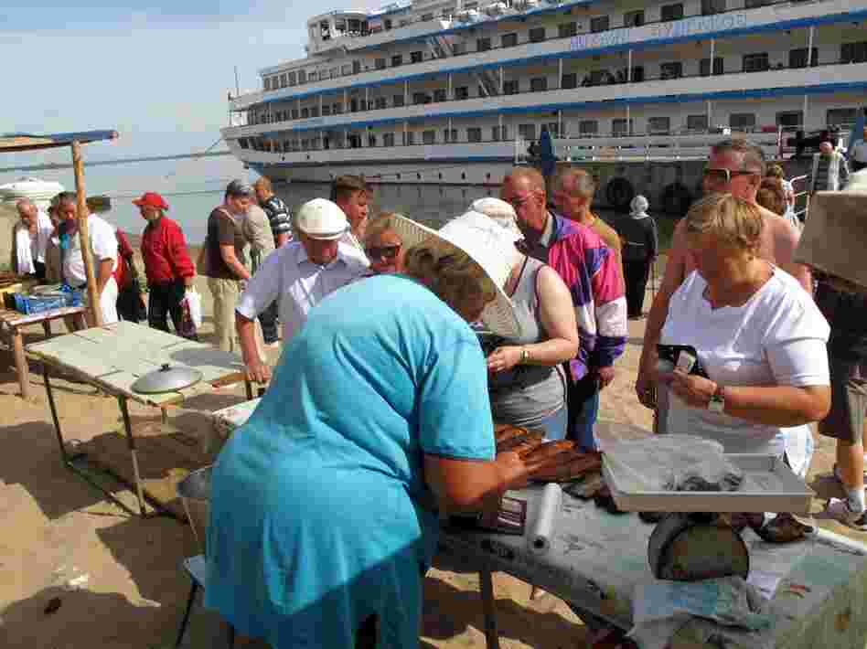At one of the many port stops, travelers can purchase a variety of goods, like smoked fish, from locals.