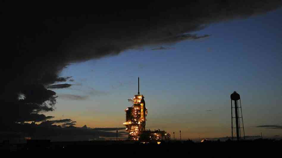 A storm cloud passes over as the US space shuttle Discovery sits on the pad at the Kennedy Space Ce A storm cloud passes over as the US space shuttle Discovery sits on the pad at the Kennedy Space Ce
