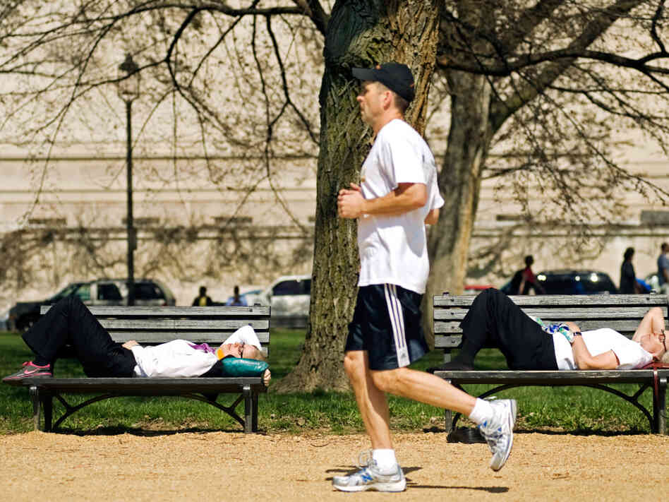 A jogger passes two women napping A jogger passes two women napping