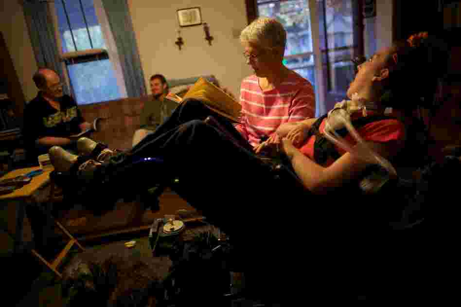 Welter's mom, Tamara, reads to her in the family's living room with her father John and brother Brian in Lincoln, Ill. Now, nurses care for Welter 16 hours a day. John and Tamara take over the other eight hours. If they lose the funding for Olivia's care, the Welters will become her round-the-clock caregivers.