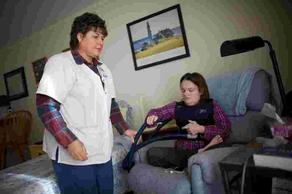 Nurse Vicki Hagen comes over to Beckett's apartment in Cedar Rapids, Iowa, to help fit her with a vibrating vest that helps clear mucous from her lungs twice a day. Studies have shown that, almost always, it costs less to care for someone at home than in a nursing home or hospital.