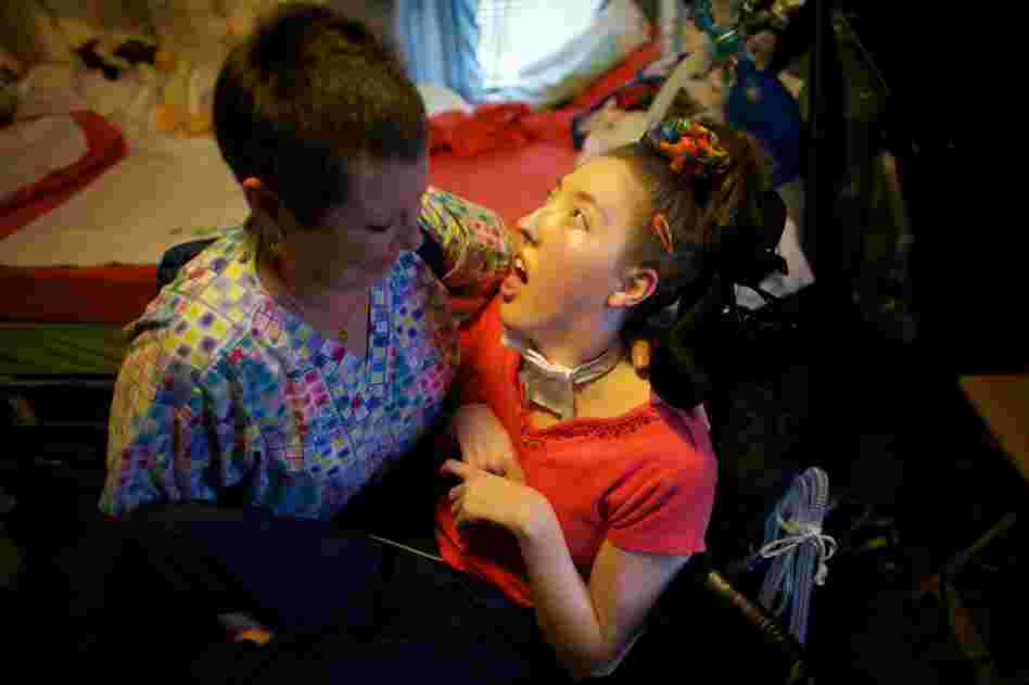 Nurse Helen Houchins moves Welter from her bed to a wheelchair.  Welter needs 24-hour care and she breathes with the help of the portable ventilator on the back of her wheelchair. She can't speak, can't move and can't even close her eyelids — her eyes are wide open.