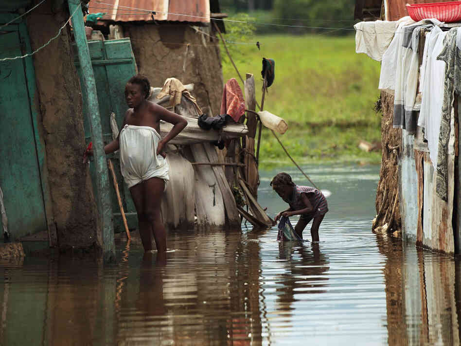 People stand outside homes in Petite Riviere, Haiti, that were flooded by Hurricane Tomas. People stand outside homes in Petite Riviere, Haiti, that were flooded by Hurricane Tomas.