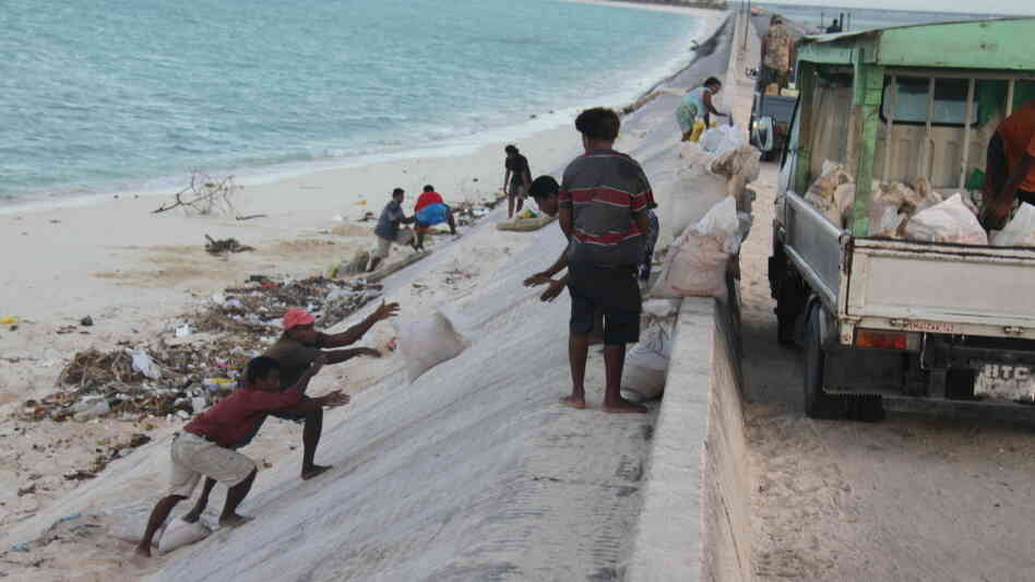 People mine bags of sand along a causeway in South Tarawa. People mine bags of sand along a causeway in South Tarawa.