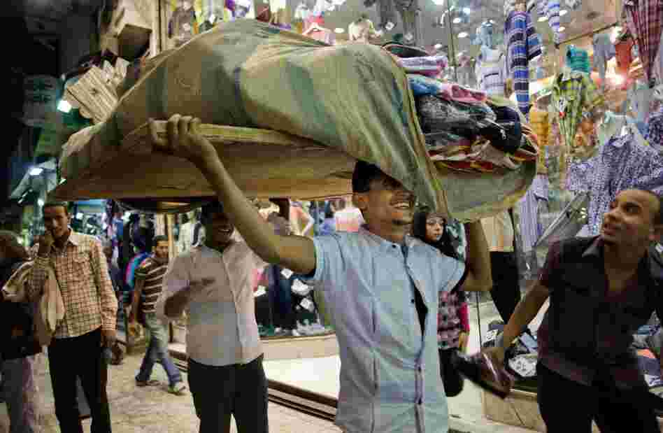 A vendor moves a portable table full of goods. Vendors open the sack at the top to make it easy to run in case the police come to clear them and their merchandise away.