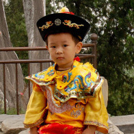 A Chinese family coaxes their son to pose in a "little emperor" costume at a Beijing park