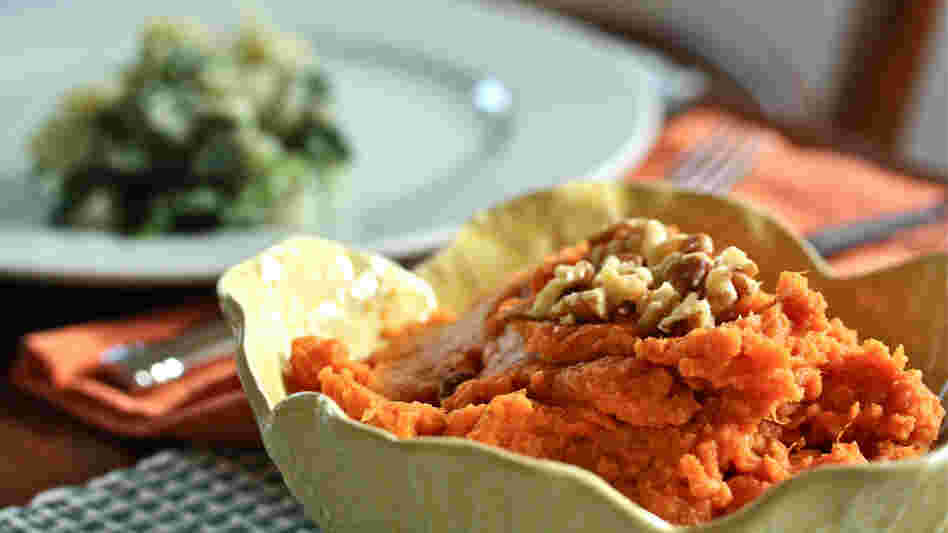 Thanksgiving table set with dishes of greens and sweet potato mash