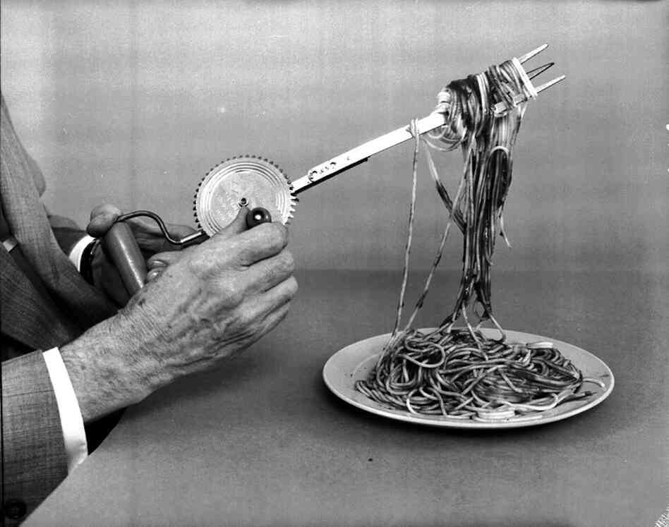 A wind-up spaghetti fork in operation, devised by Oakes. The fork winds spaghetti strands making them easy to eat. 
