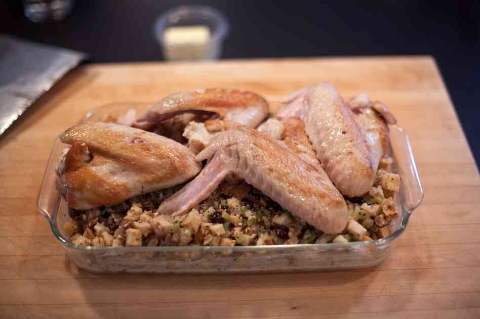 Simmer turkey wings in a skillet before placing on top of the stuffing, and bake for over an hour.