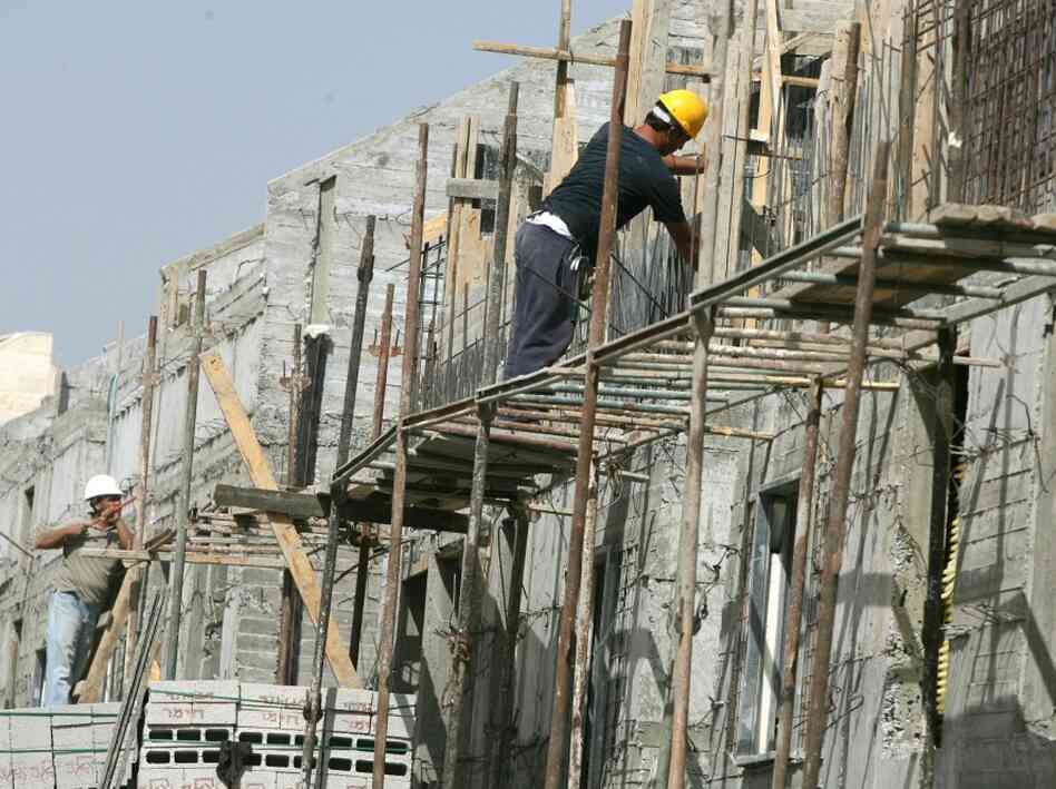 Palestinian laborers work in a new section to the Jewish settlement of Kiryat Arbaa. Palestinian laborers work in a new section to the Jewish settlement of Kiryat Arbaa.