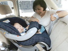 A woman secures a child in a rear-facing car seat in the back seat of a vehicle. A woman secures a child in a rear-facing car seat in the back seat of a vehicle.