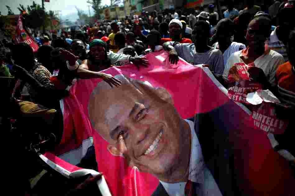 Supporters carry a giant poster of Martelly in a massive demonstration. Officials acknowledged that the election was imperfect, with hundreds of thousands of earthquake dead still registered and many living voters waiting for ID cards.