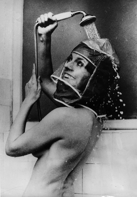 To prevent her makeup from running and her hair from getting wet, an actress demonstrates the "new" shower hood, which probably had the effect of steaming her makeup right off. 