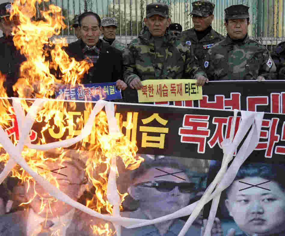 South Korean veterans burn a banner showing photos of North Korean leaders. South Korean veterans burn a banner showing photos of North Korean leaders.