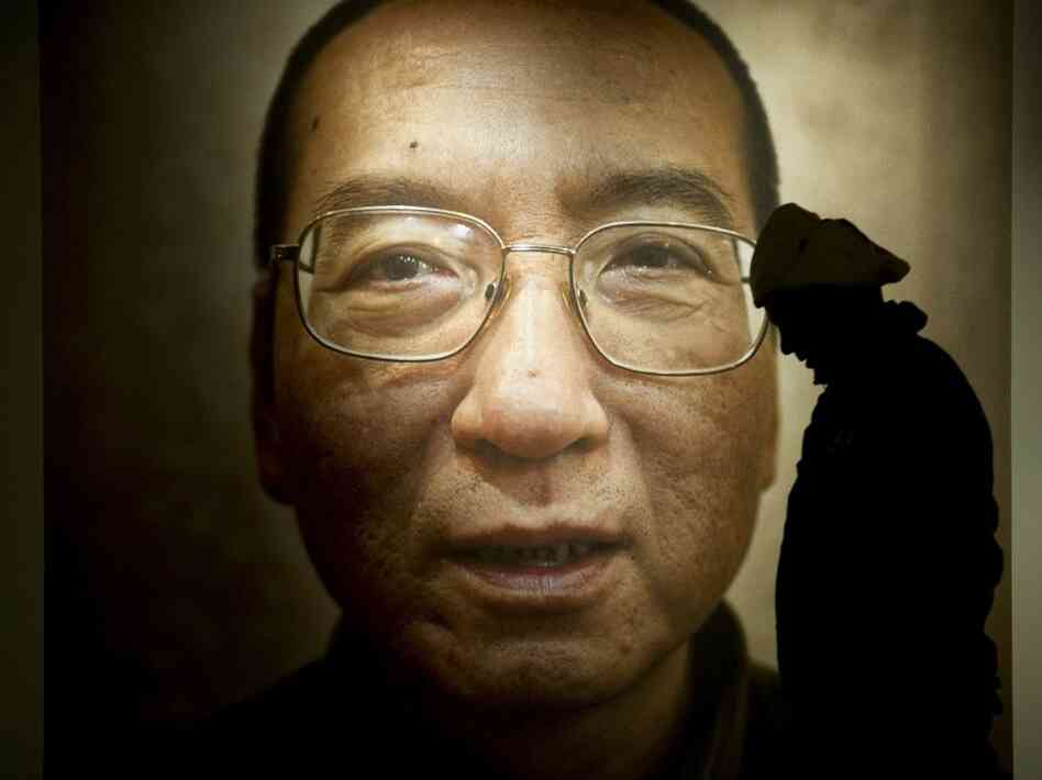A man in Oslo walks in front of a poster of Liu Xiaobo. A man in Oslo walks in front of a poster of Liu Xiaobo.
