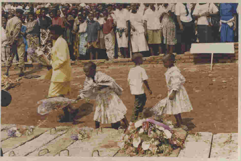An undated image shows three children and a woman laying wreaths on a mass grave of genocide victims An undated image shows three children and a woman laying wreaths on a mass grave of genocide victims