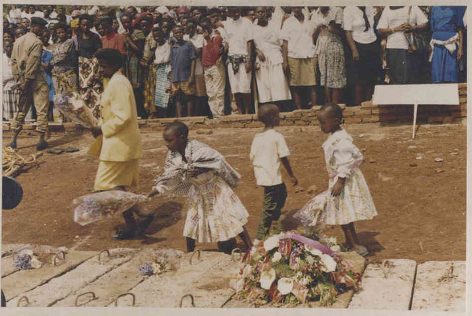 An undated image shows three children and a woman laying wreaths on a mass grave of genocide victims An undated image shows three children and a woman laying wreaths on a mass grave of genocide victims