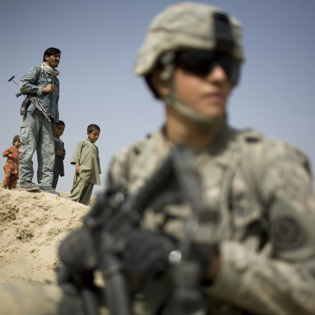 Children and an Afghan policeman look at a U.S. soldier on patrol in Kandahar