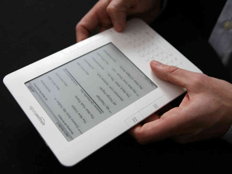 A Kindle e-reader in someone's hands. A Kindle e-reader in someone's hands.