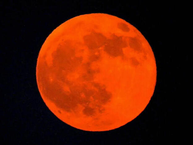 The moon appears red during a lunar eclipse in the Qatari capital of Doha, 28 August 2007. It's going to happen again tonight, and be visible across North America.