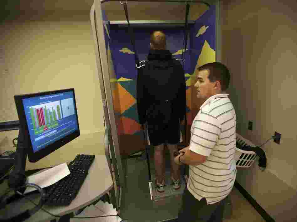 Brendan Jannesen, 23, works with Brian Smith (right), a physical therapist, on issues with his knee. Jannesen, who was injured in Afghanistan while working as a Forward Observer for the Army, is strapped into a machine that measures his body's responses to abrupt balance changes. 