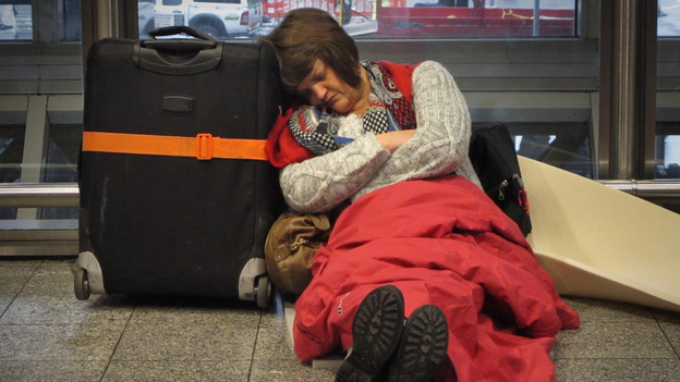 A passenger sleeps on the floor as she waits for a  flight from Terminal 3 at Heathrow airport Tuesday in London.