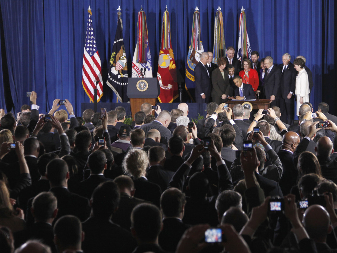 As President Barack Obama signed the Don't Ask, Don't Tell Repeal Act, Rep. Steny Hoyer, Sen. Susan Collins and Sen. Joe Lieberman (obscured behind Collins) stand at the edge of the stage.