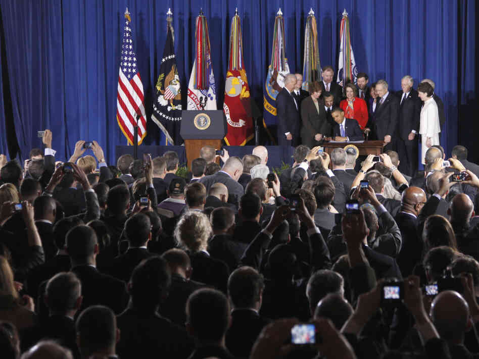 As President Barack Obama signed the Don't Ask, Don't Tell Repeal Act, Rep. Steny Hoyer, Sen. Susan Collins and Sen. Joe Lieberman (obscured behind Collins) stand at the edge of the stage.