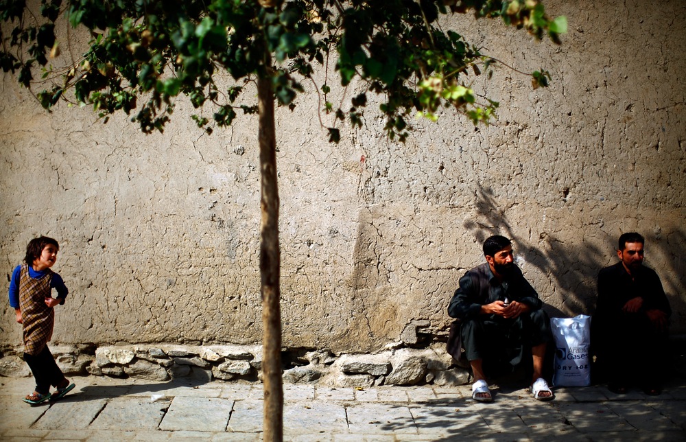 A girl runs past men sitting in the shade in the Old City. In recognition of Murad Khane's unique value as one of the last remaining sites of such a traditional urban environment, it was listed on the World Monuments Fund's 2008 Watch List.