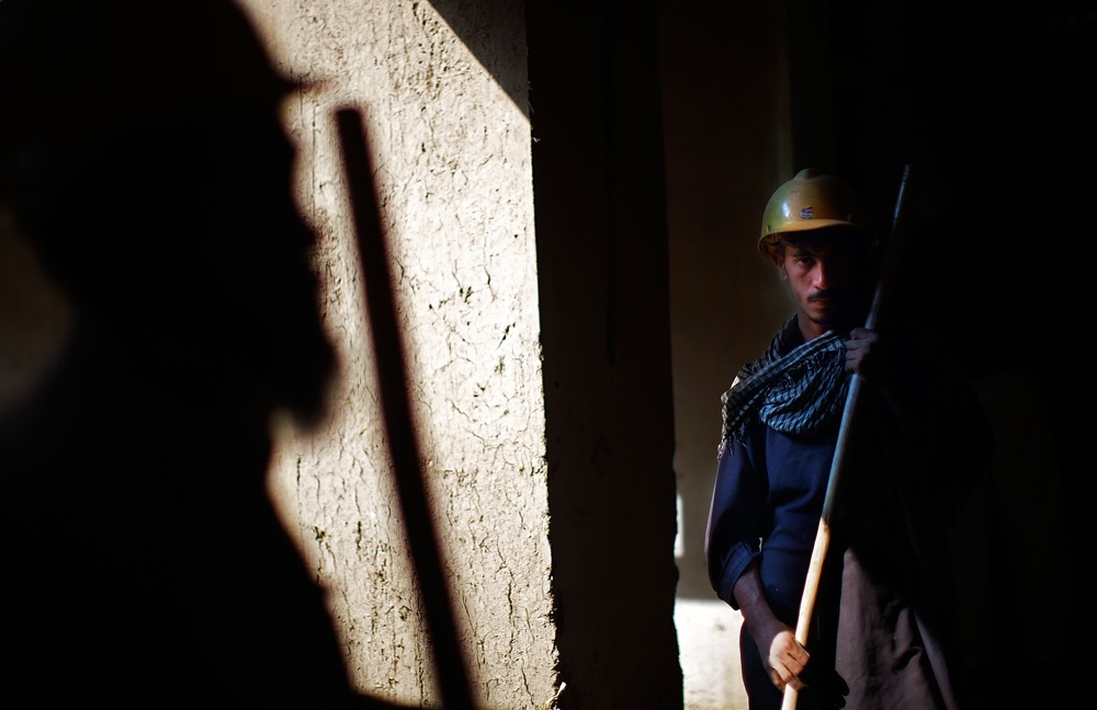 Afghan craftsmen stand in the evening light.